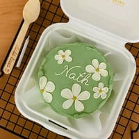 Bento cake delicado com flores claras num fundo verde